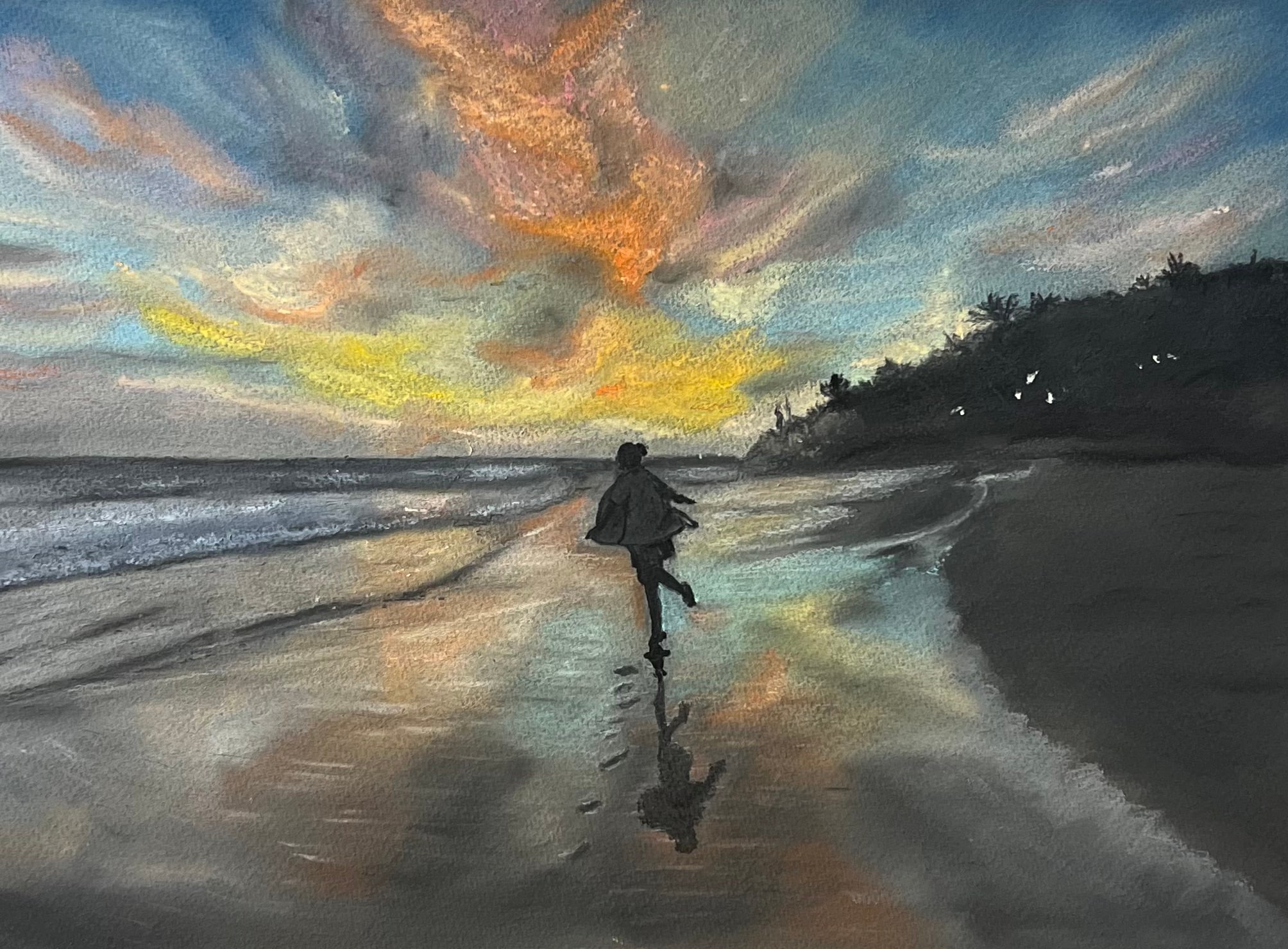 A girl in a loose coat runs along wet sand toward the sea, her reflection trailing beneath her, under a sky streaked with yellow, peach and blue.